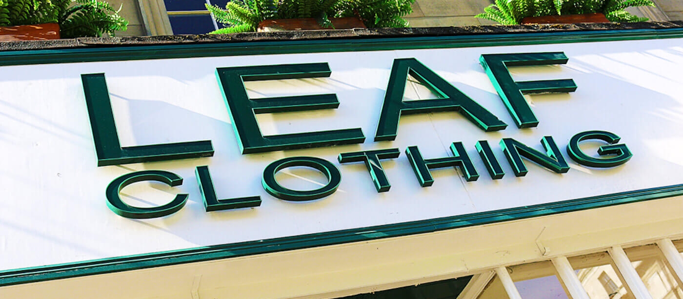 The Leaf Clothing shopfront sign on Pilgrim Street, racing green lettering on a cream panel with ferns spilling from upper window planters